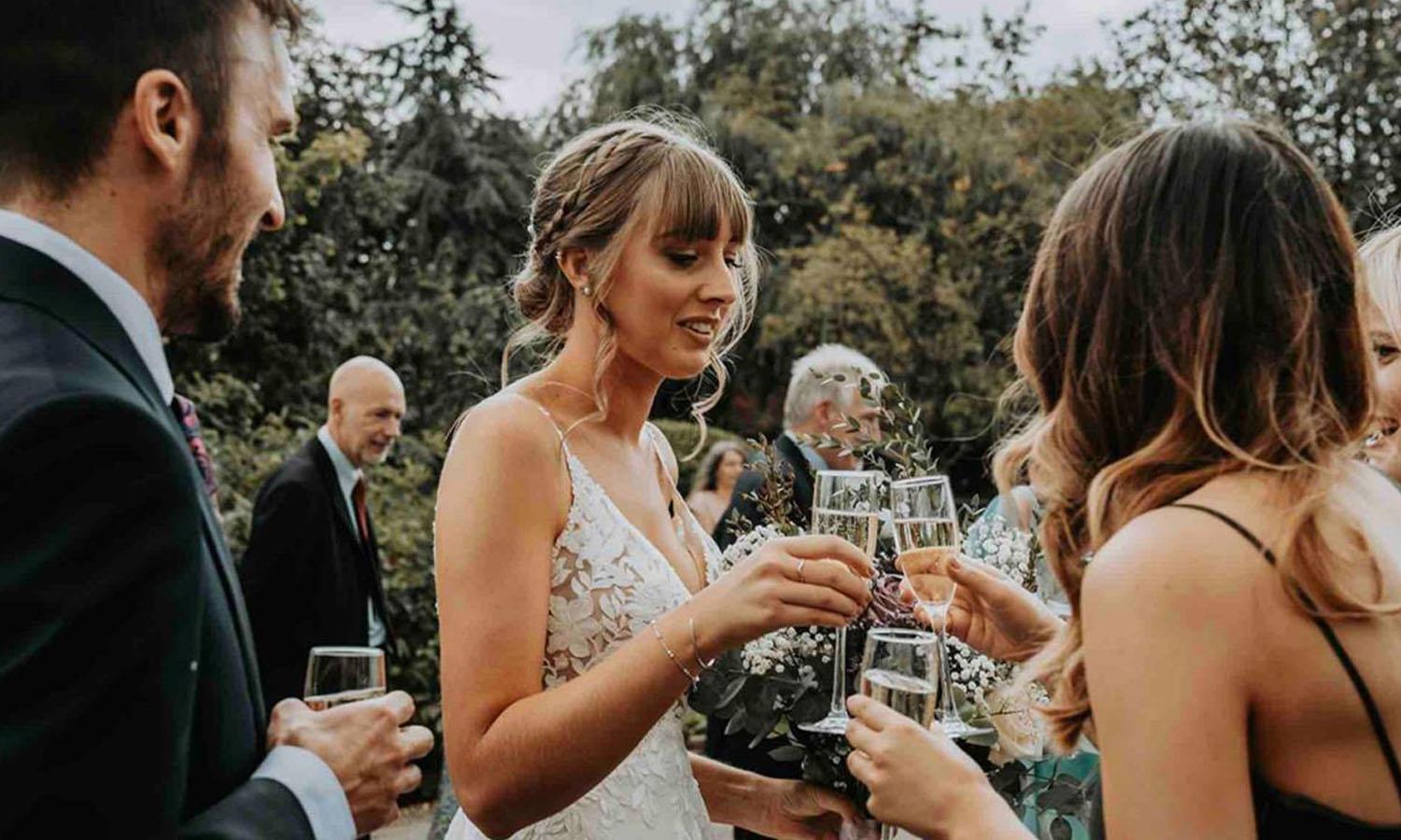 Bride and groom toasting their wedding with guests in Widbrook's gardens