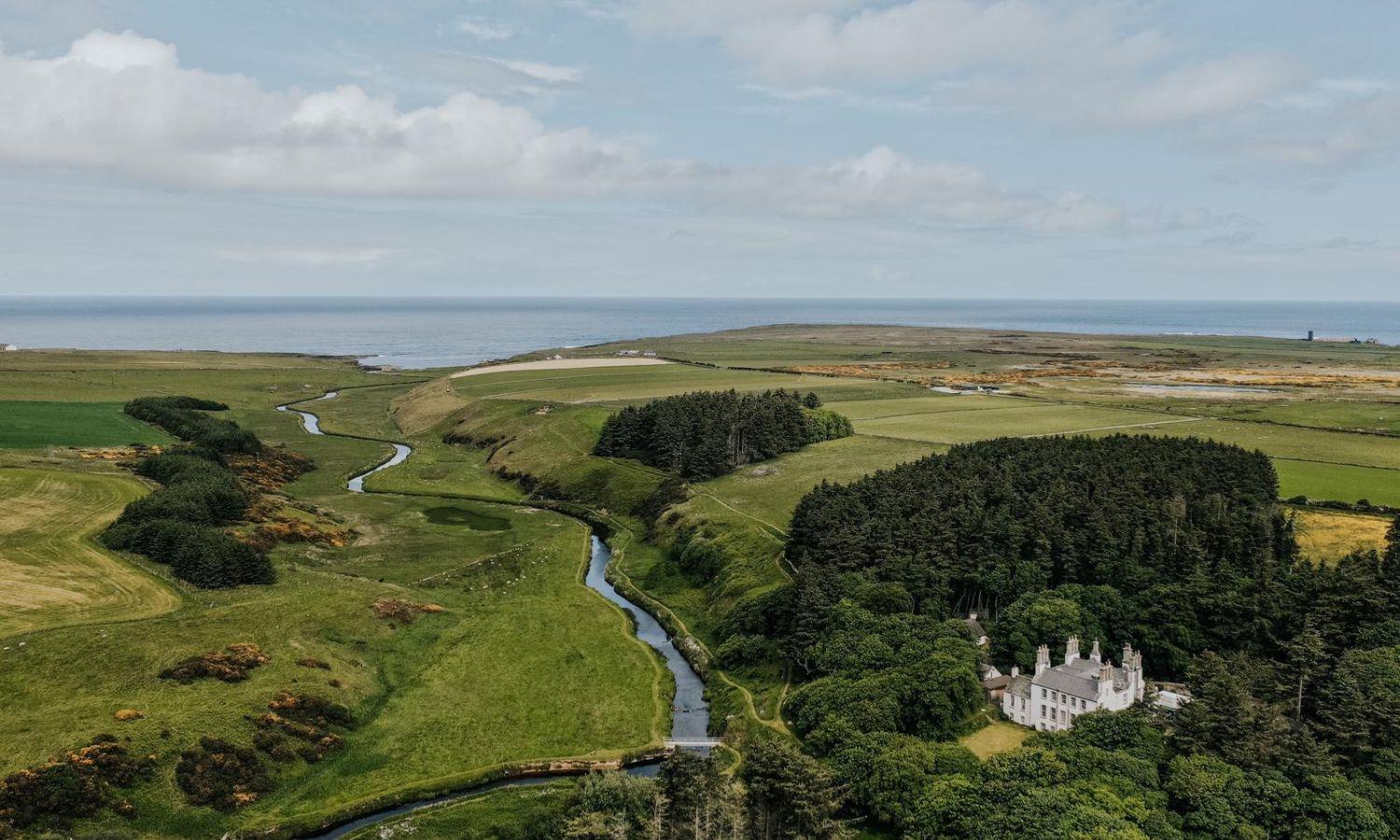 Drone photo of Forss house Hotel showing hotel, woodland, and coastline