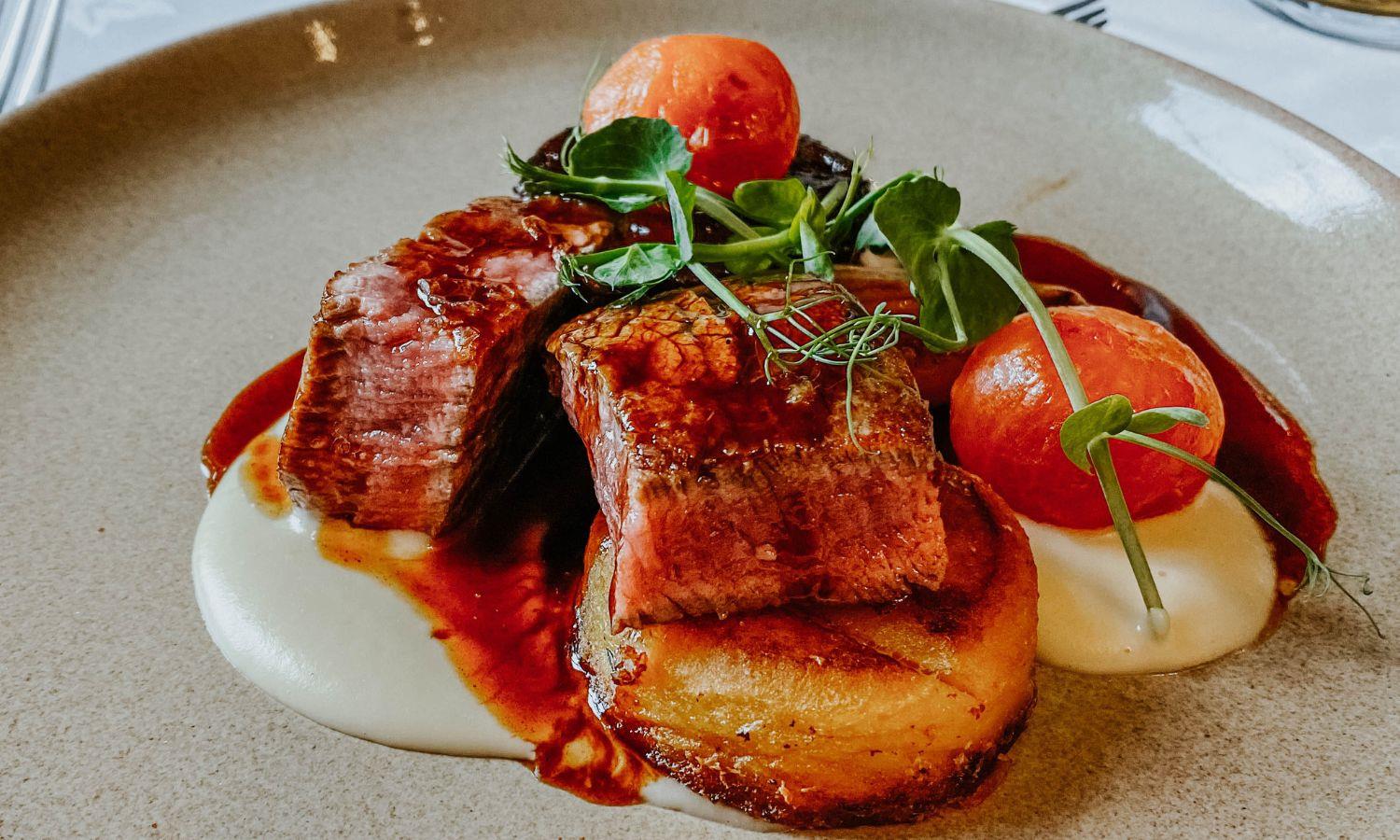 Highland beef on a plate with tomatoes and pea shoots