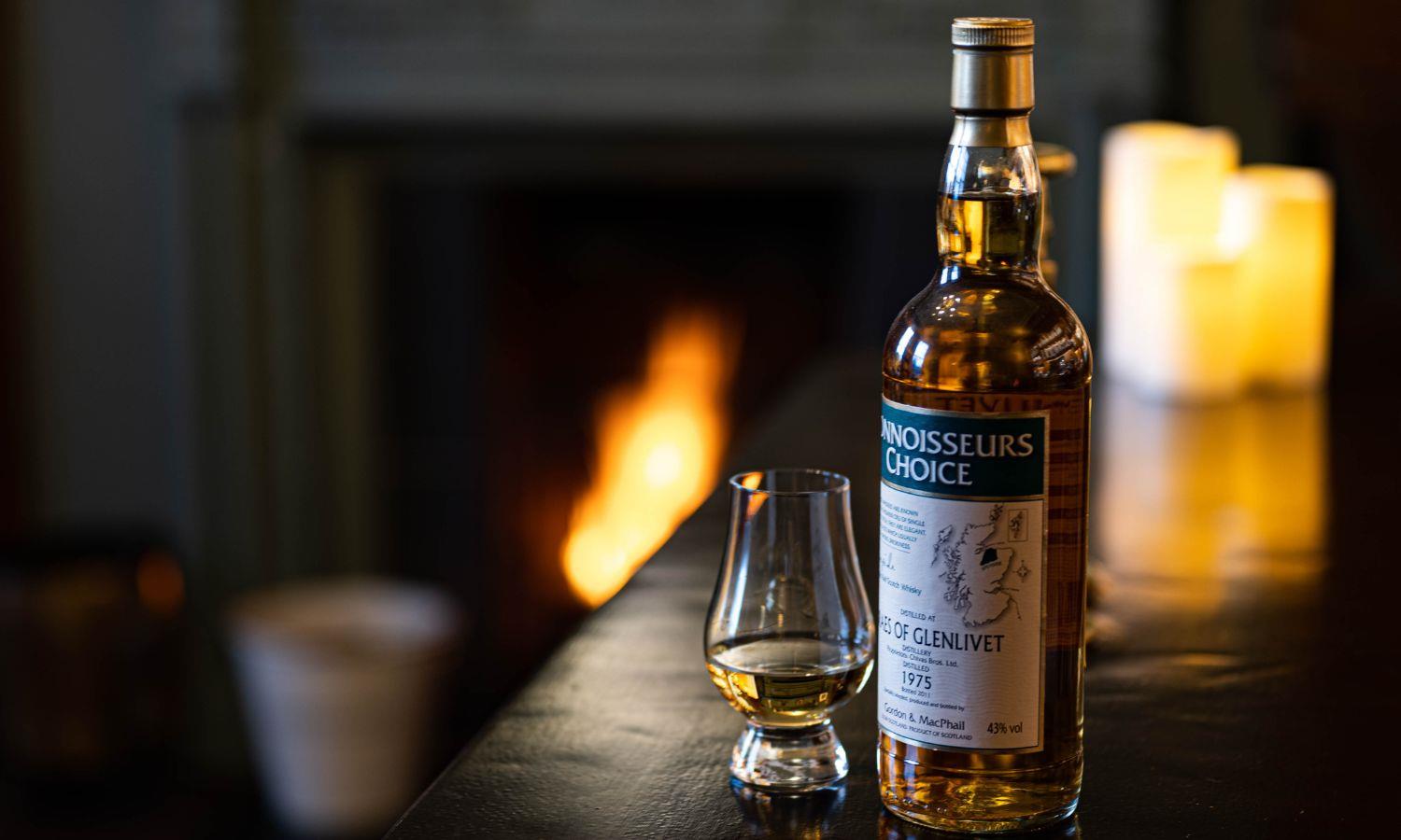 Whisky on the bar with candles and cosy log fire in background