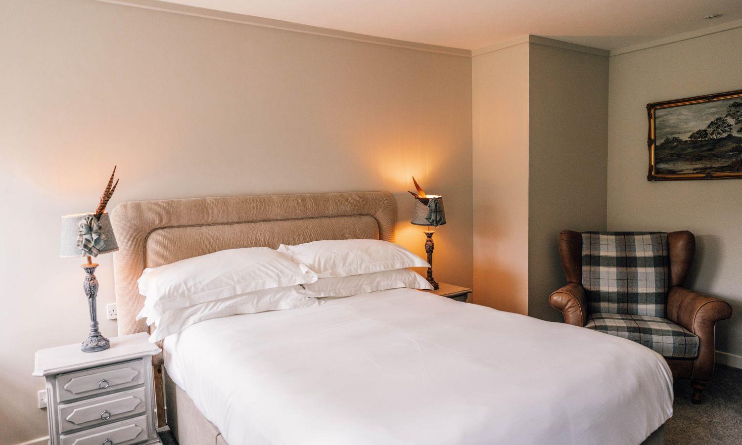 Double bed in boutique hotel bedroom with chair and bedside cabinet