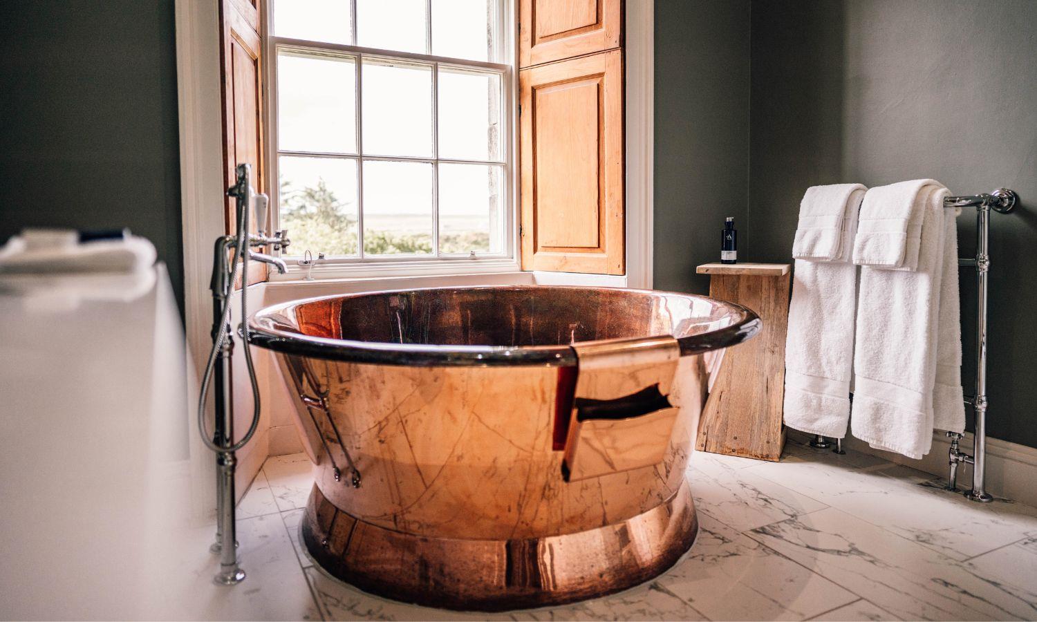 Giant round copper bath in hotel bathroom with window