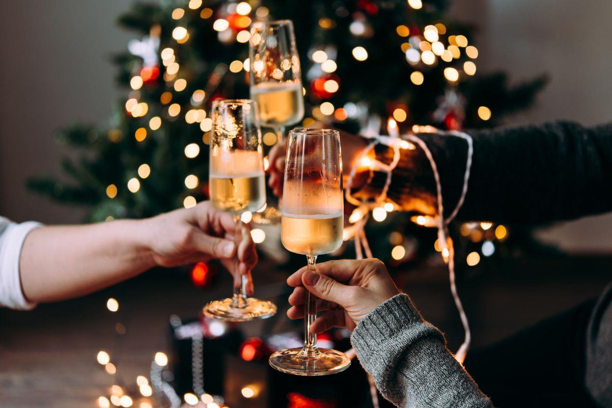 A cheers with Champagne glasses in front of a Christmas tree