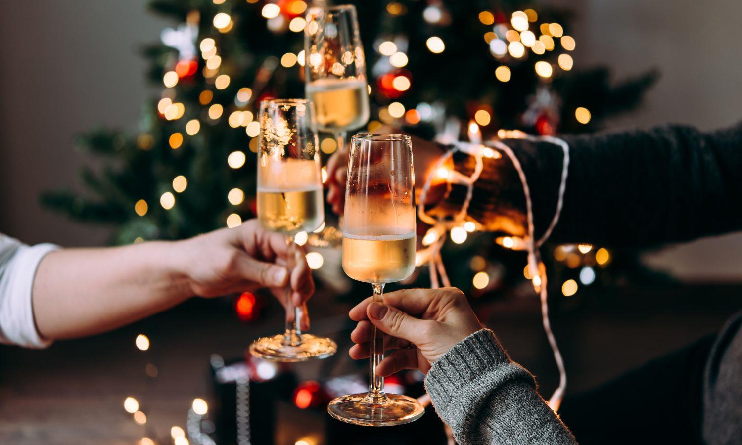 A cheers with glasses of Champagne in front of a Christmas tree