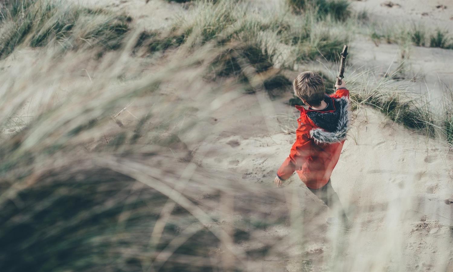 Child in red coat in sand dunes