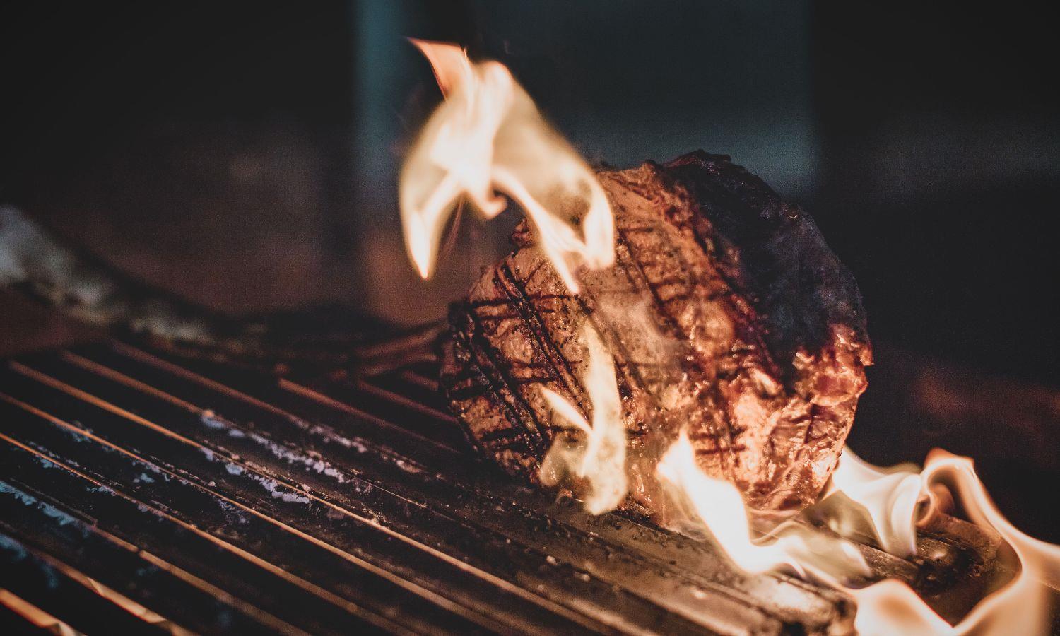 Steak being flame grilled on barbecue