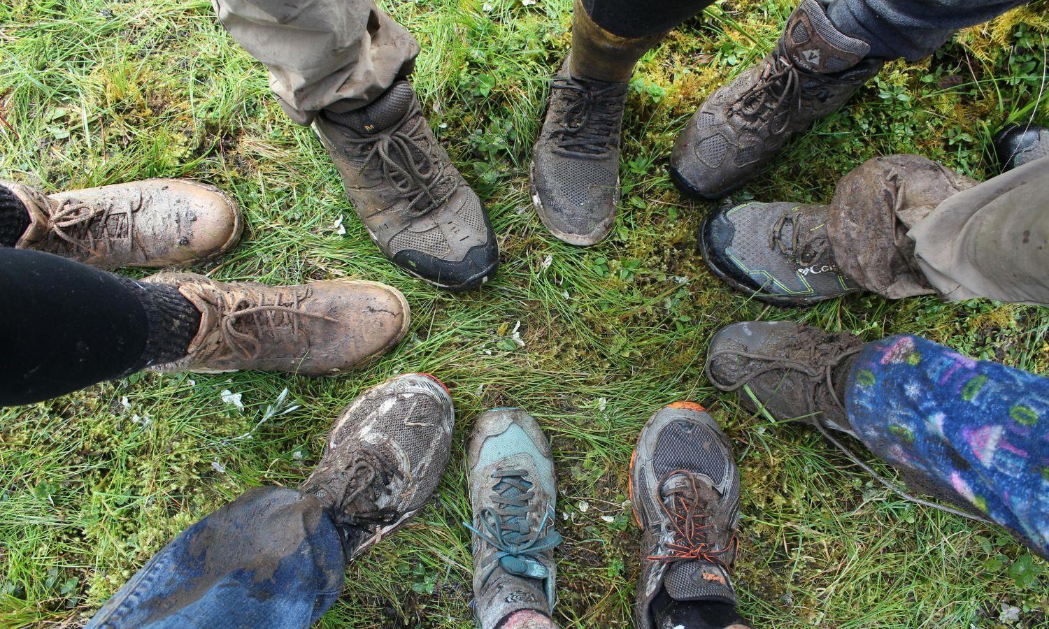 People in muddy hiking boots, each with one foot in a circle formation