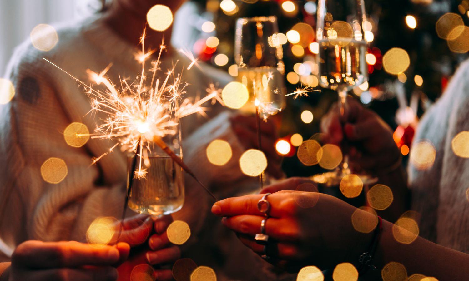Sparklers and champagne with festive lights reflected 