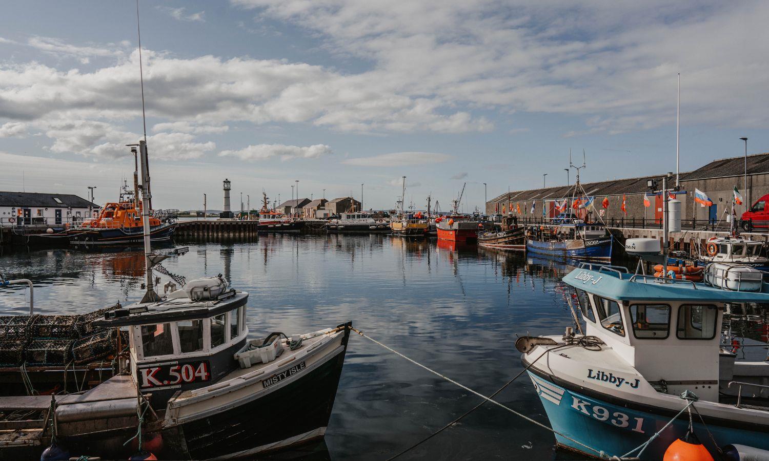 Boats floating in Kirkwall Harbour on a bright, slightly cloudy day