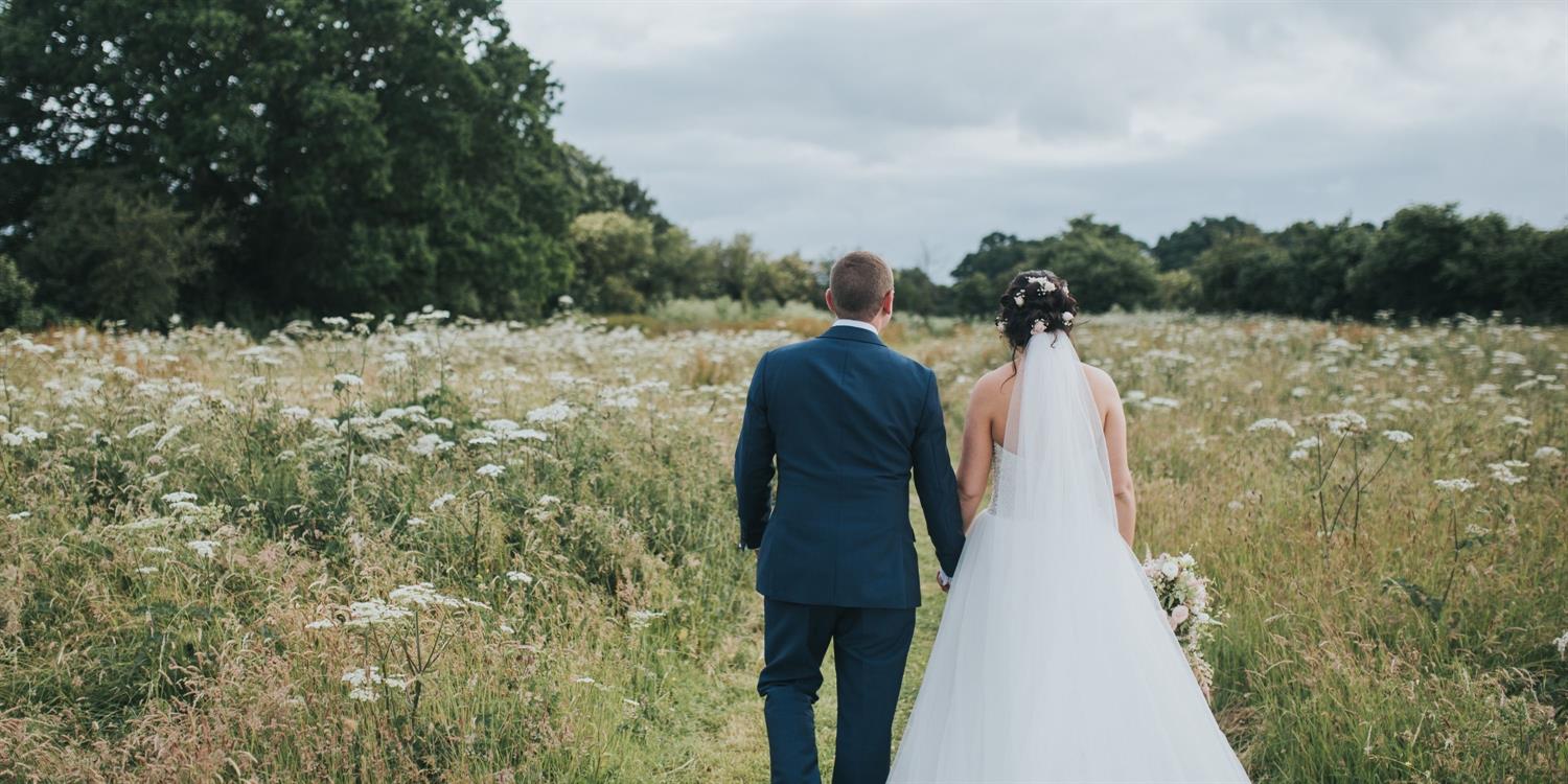 Wedded couple walking in meadow
