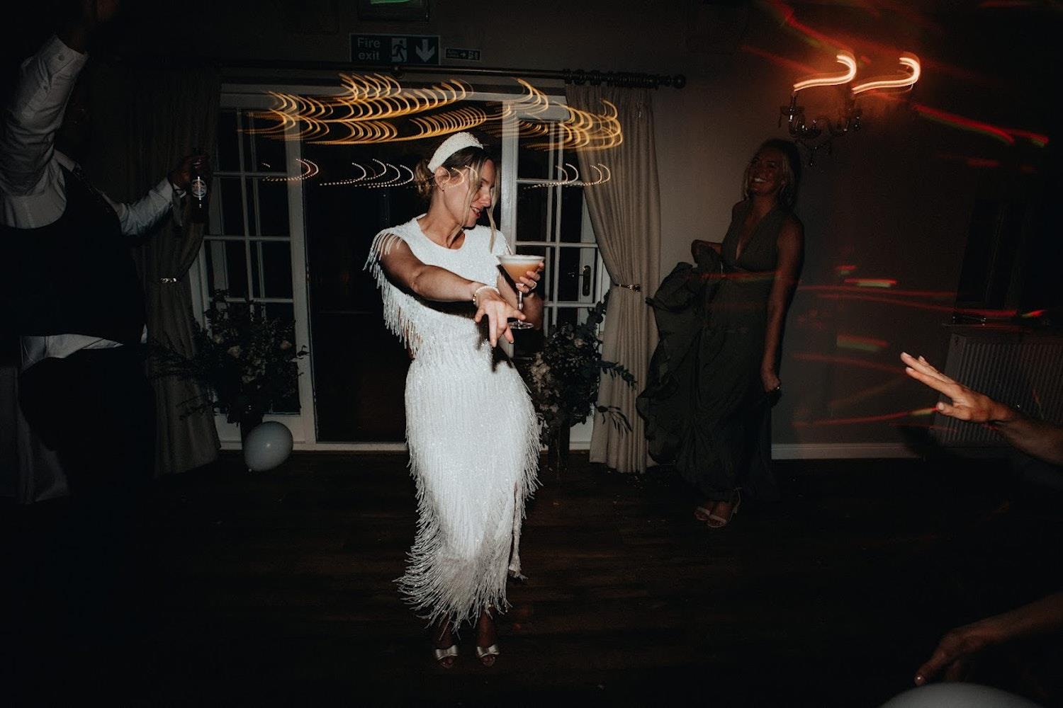Bride on the dance floor holding a cocktail (c) Jacob Malinski