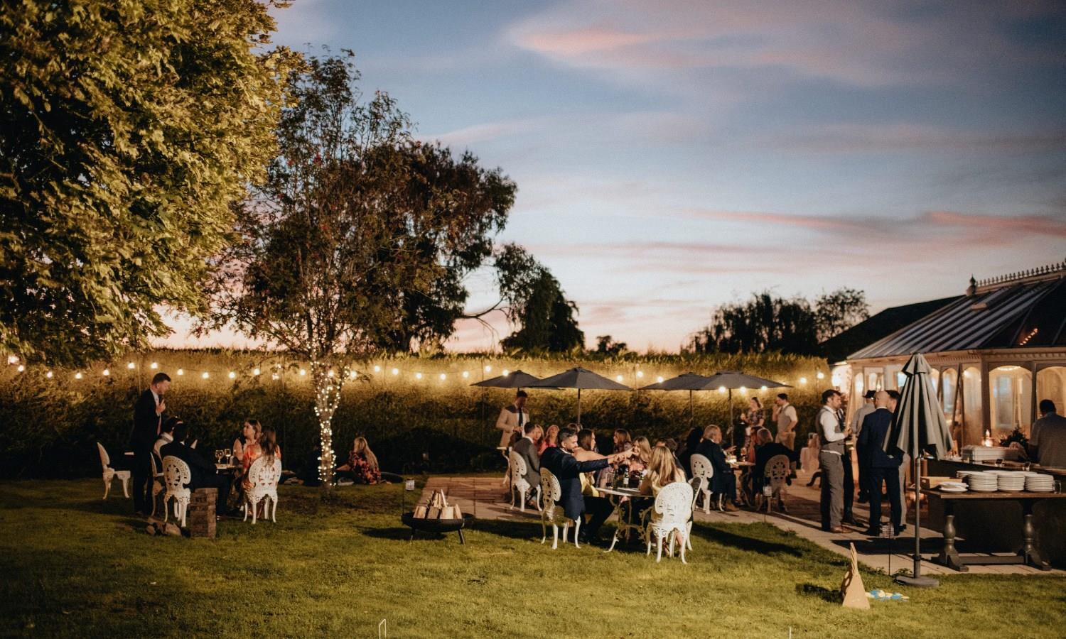 Outdoor wedding party in twilight with guests relaxing