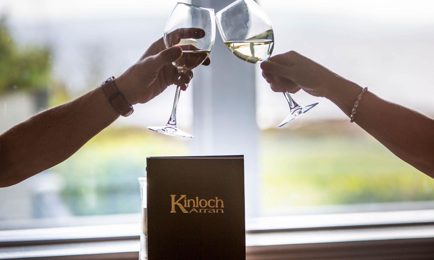 Guests raising a glass of wine in the Kinloch Hotel restaurant overlooking the coast on Arran