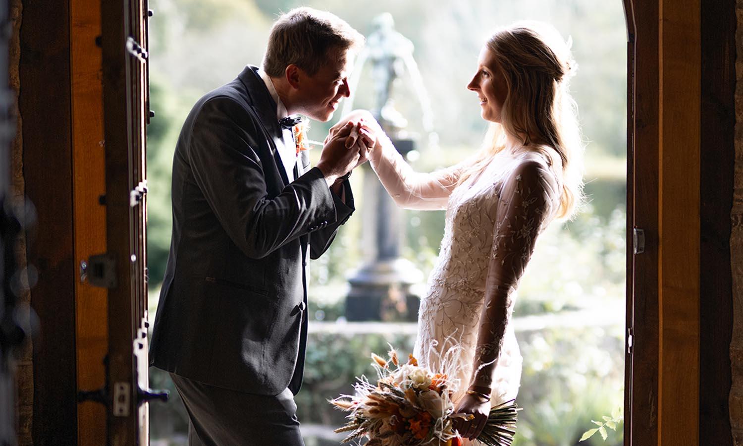 Groom kisses bride's hand at front door of 