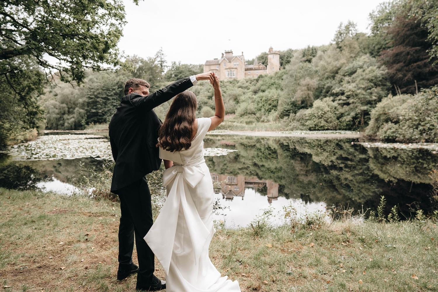 Bridal couple by lake with view of Auchen Castle