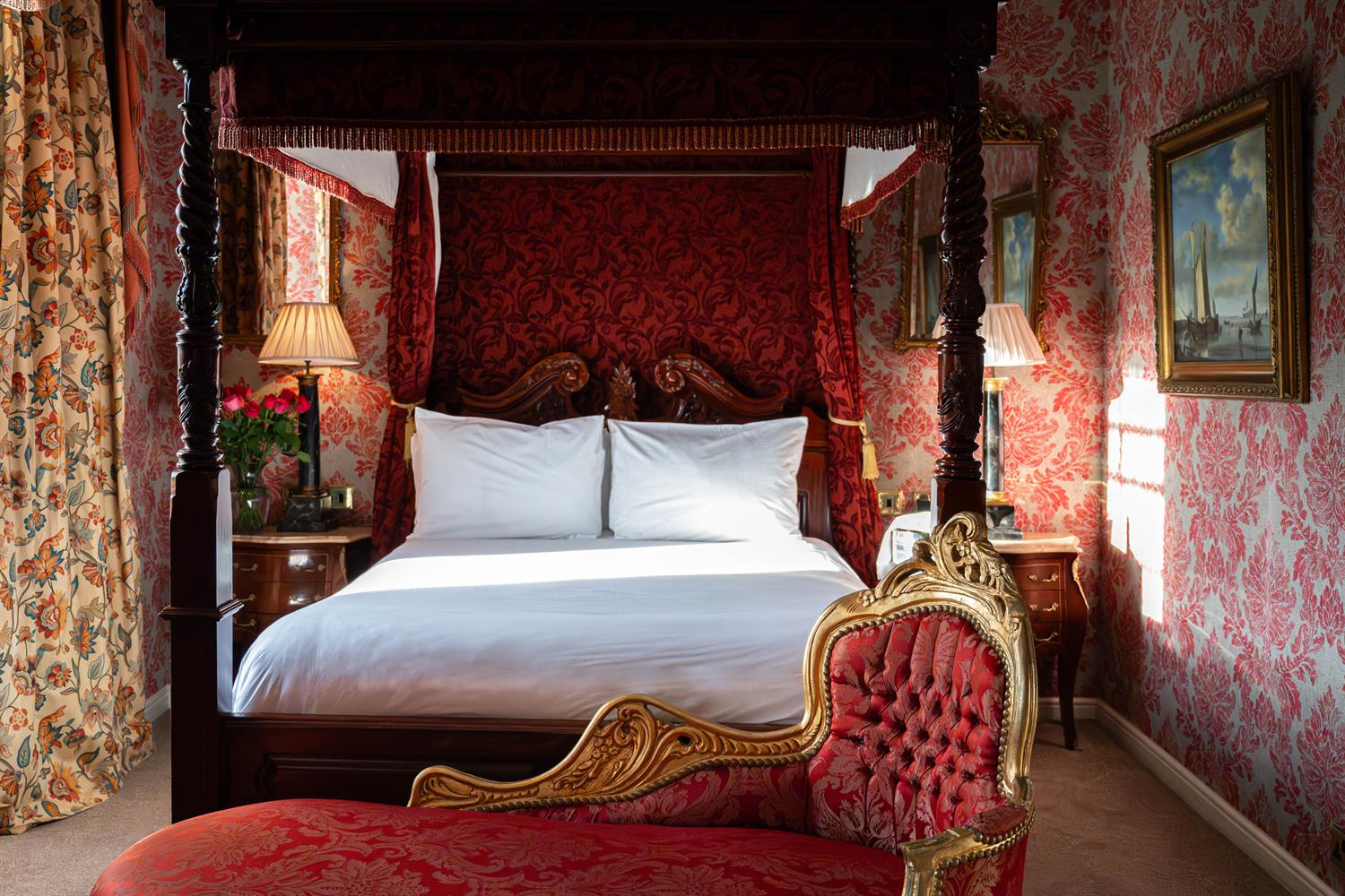 Luxurious looking bedroom with a four-poster bed filled with natural light from the castle windows