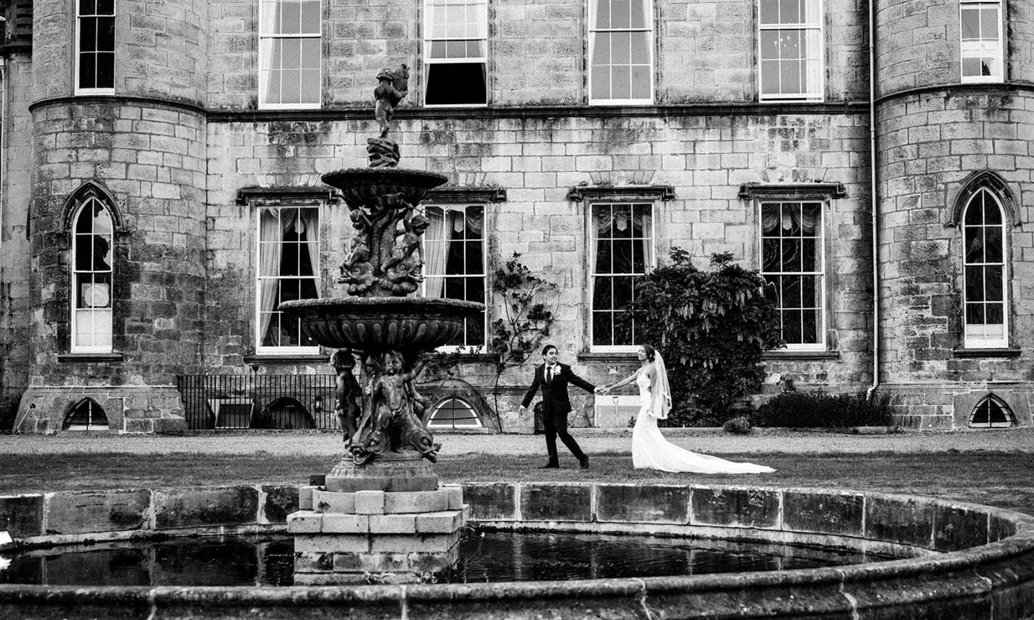 Wedding couple holding hands by Melville Castle