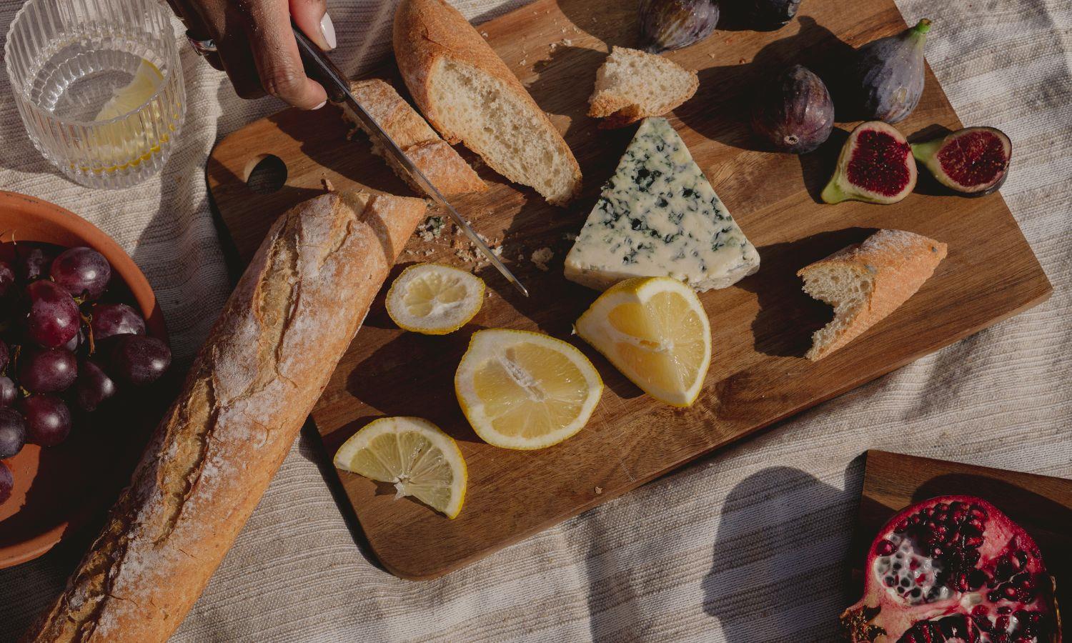 Artisan picnic board with bread, cheese, grapes, figs and fresh fruit on a blanket