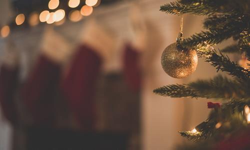 Gold bauble hanging from a Christmas tree