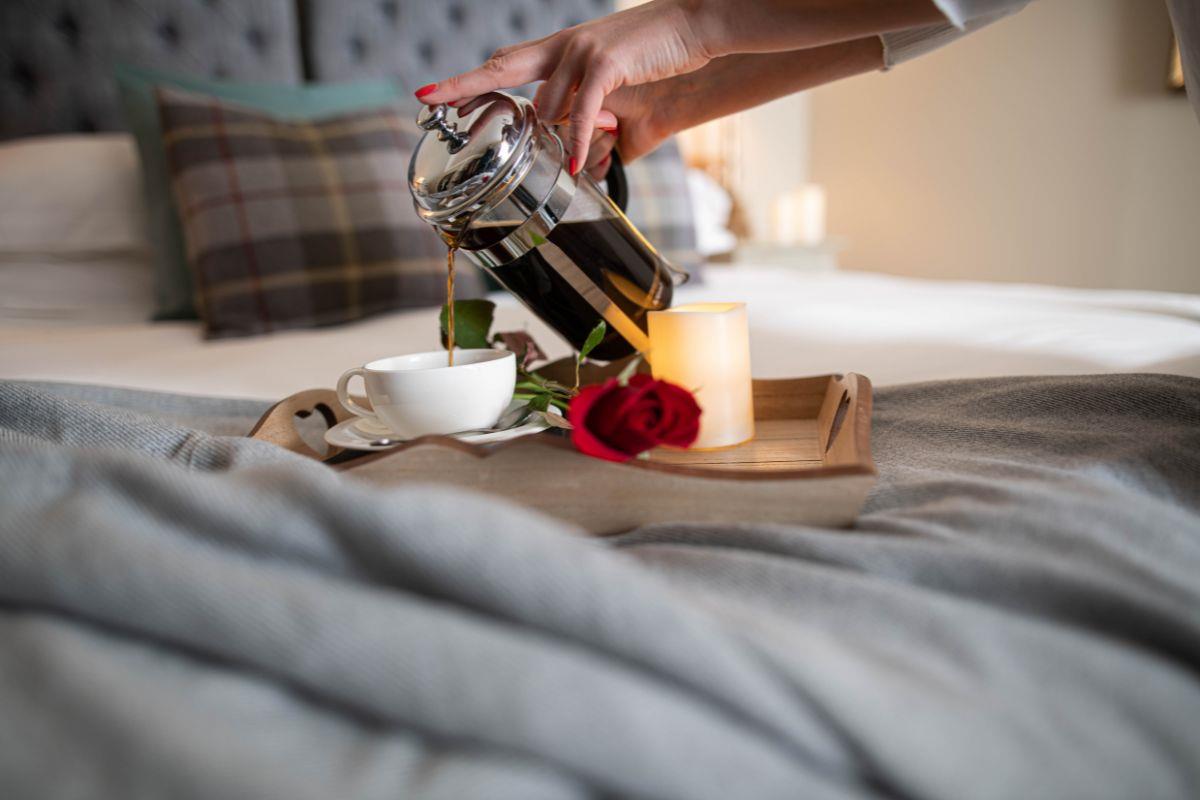 Coffee tray on a bed with a red rose
