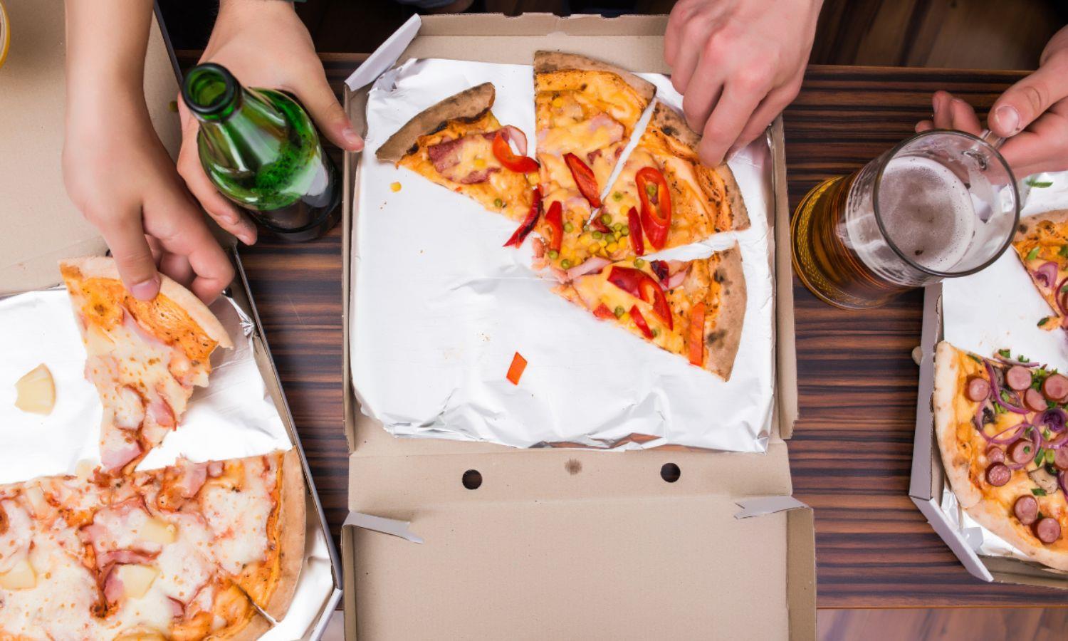 Hand picking up a piece of pizza from a pizza box