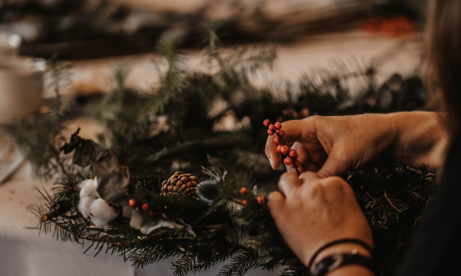 Hands putting final touches to Christmas wreath