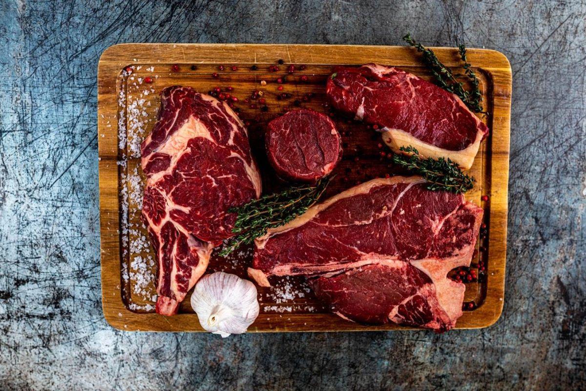 Different cuts of steak on a wooden chopping board