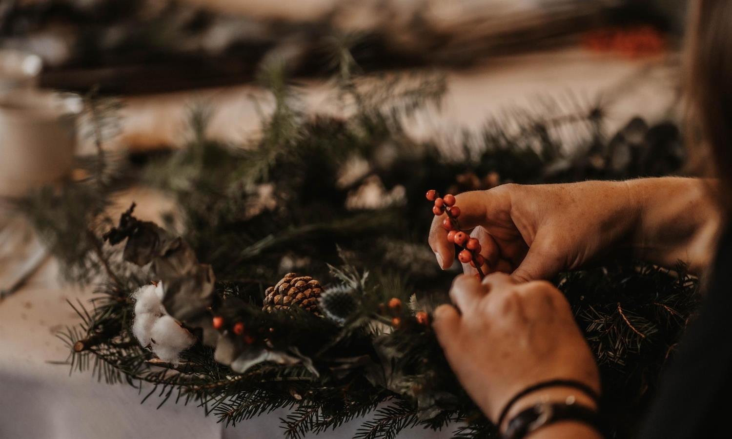 Someone adding winter berries to a Christmas wreath