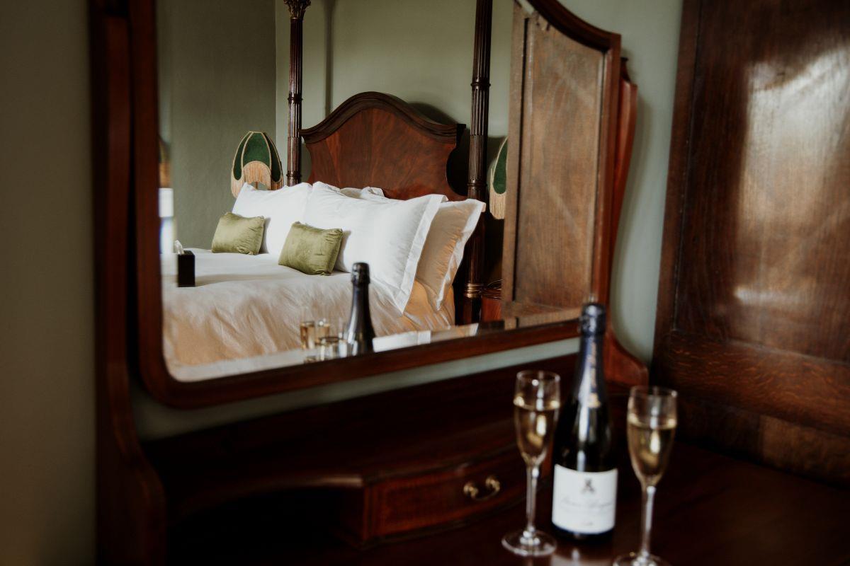 wine and glasses in front of bedroom mirror