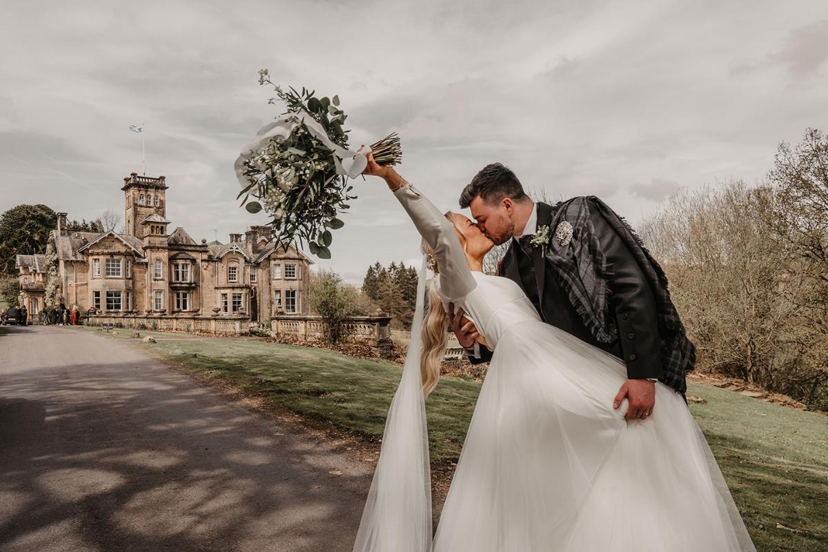 Bride and groom kissing passionately outside Auchen Castle