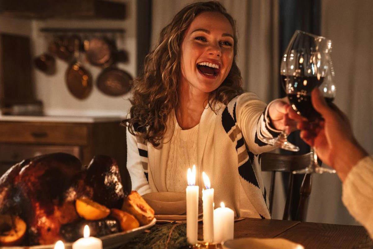 woman clinking her glass with another guest over a party meal