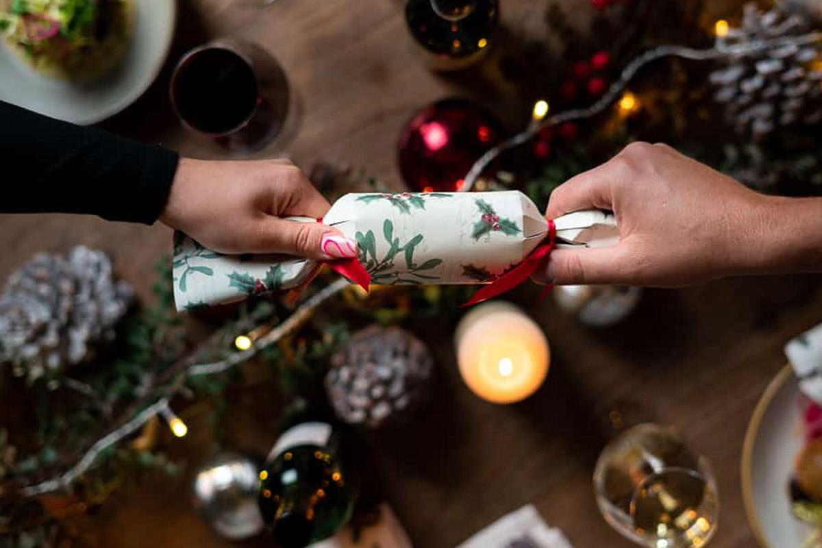 christmas cracker being pulled over table with food and fairy lights