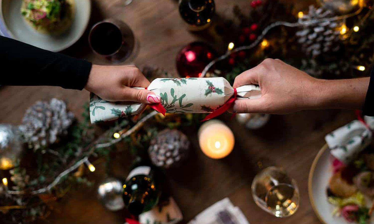 christmas cracker being pulled over table with food and fairy lights