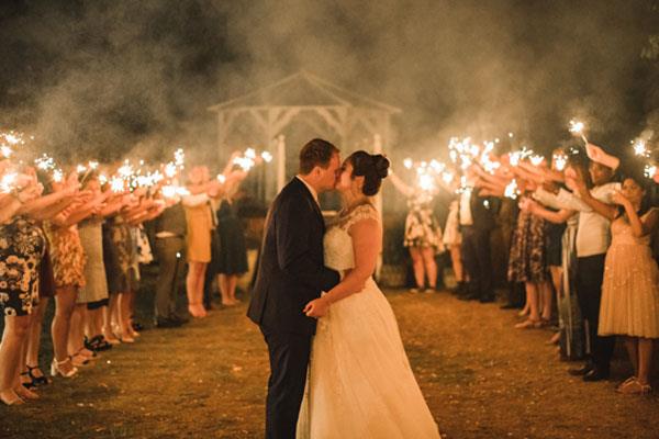 Wedded couple surrounded by friends with fireworks in background