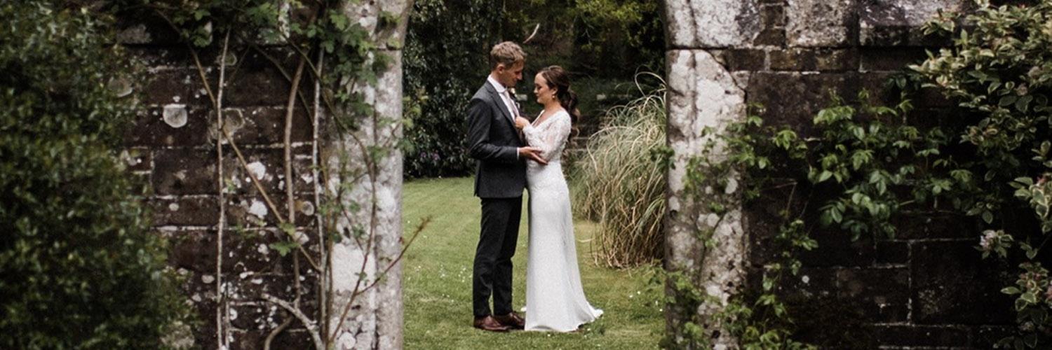 wedded couple in archway in gardens of Lewtrenchard manor