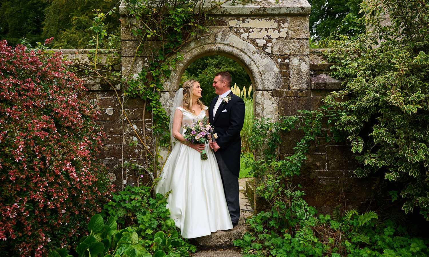 Wedding couple in an archaway in the gardens of Lewtrenchard Manor