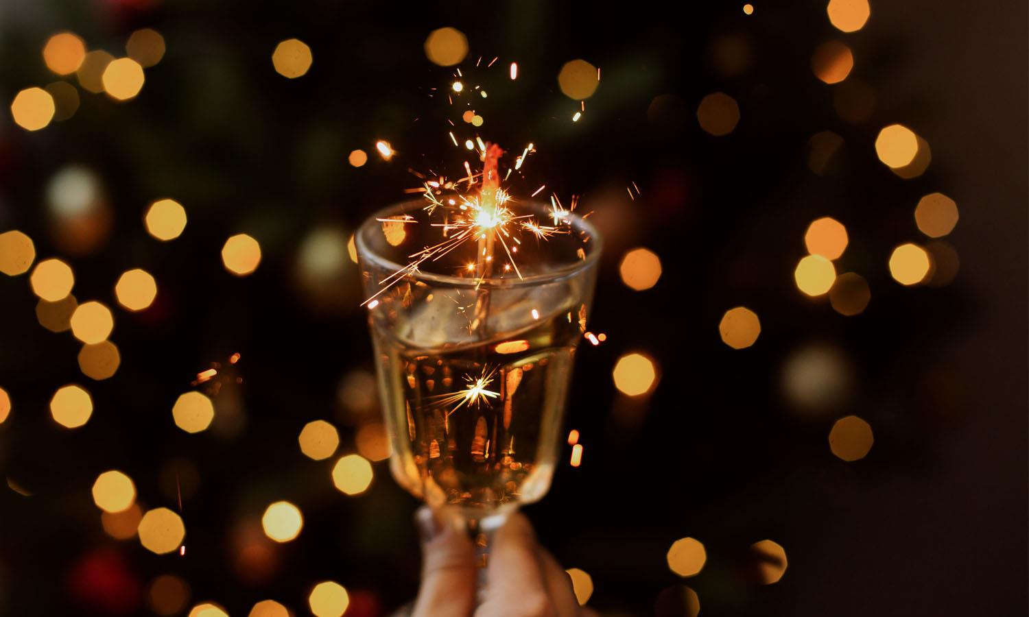 Champagne glass held in front of festive lights