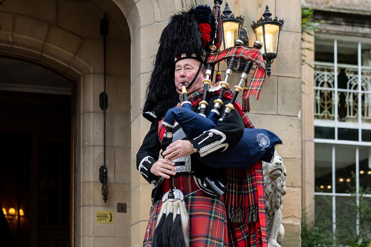 Scottish piper in full tartan at entrance to Melville Castle 
