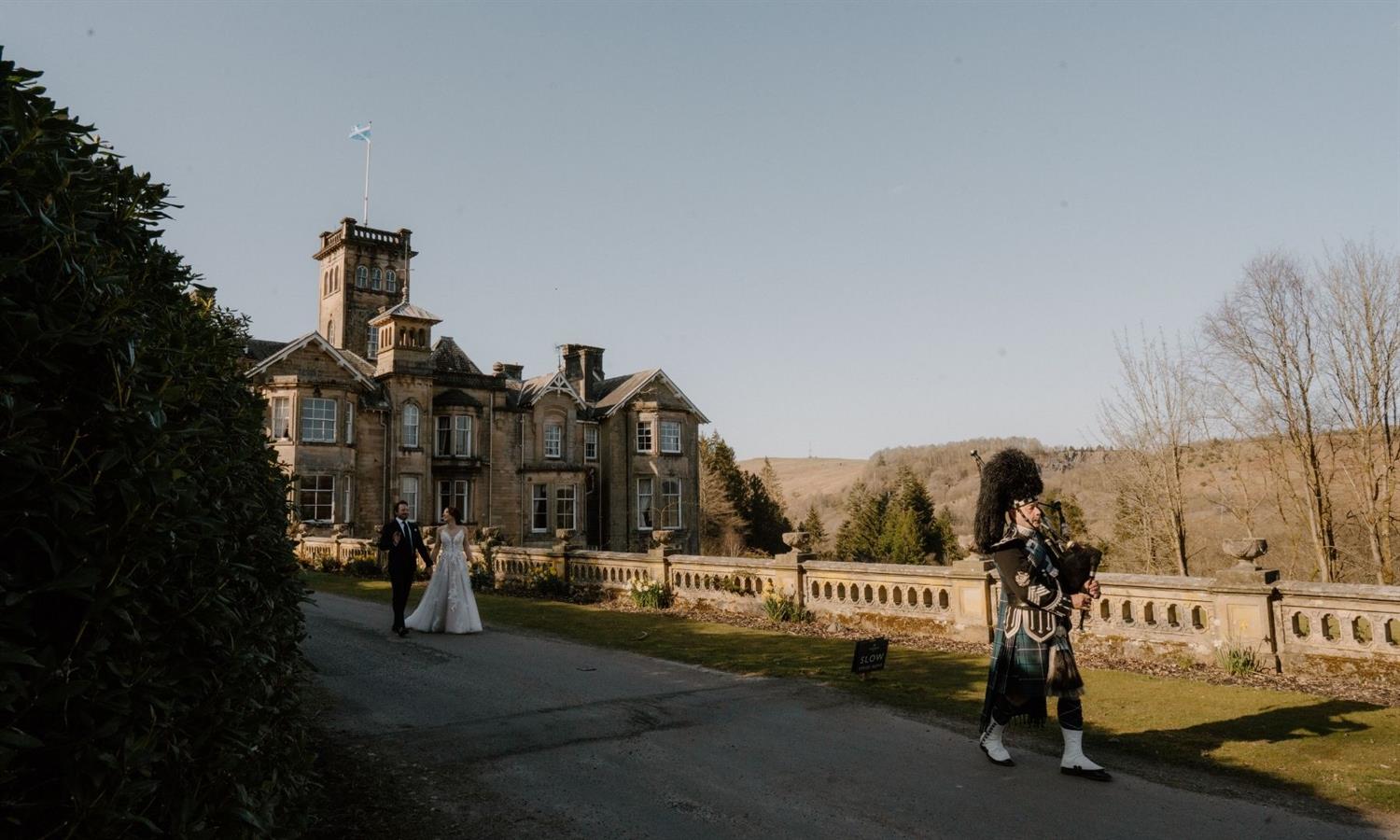 Piper leading bride and groom at Auchen Castle