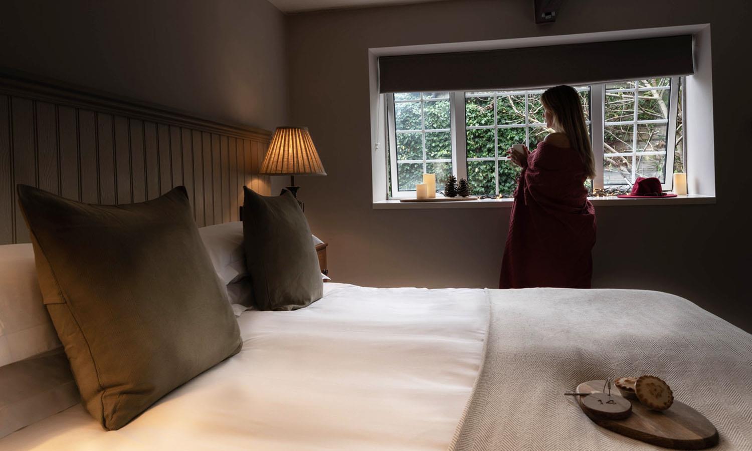 woman by bed looking out of window in Cosy Room at Widbrook Grange