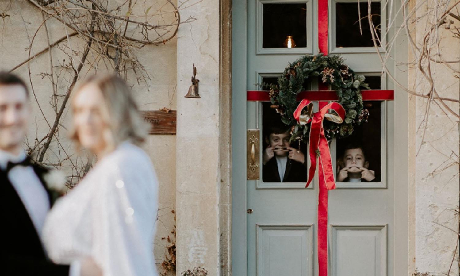 Festive wreath on Widbrook's front door with cheeky boys pulling faces at bride and groom