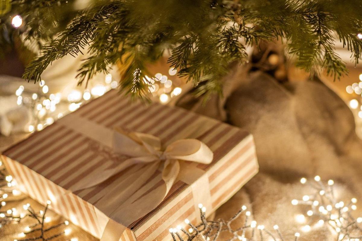 christmas presents wrapped with striped paper and ribbon on a bed of fairy lights